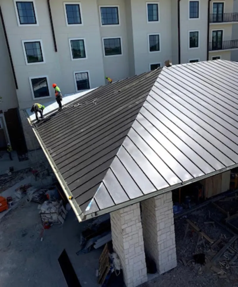 Crew installing standing seam metal roof panels on a commercial project in Genoa
